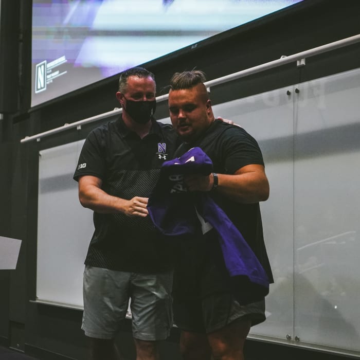 Defensive lineman Joe Spivak receives the No. 1 jersey from head coach Pat Fitzgerald.